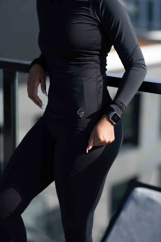 This black, raglan active top is perfect either as a base layer or to be worn over one of our sports bras. Breathable material. Perfect for a high impact workout or to add a layer to your outfit. The long sleeves have thumbholes.  91% nylon, 9% spandex. Cool-Touch technology. Moisture-wicking.
